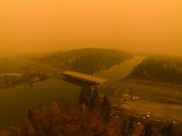 Smooky air and a river as well as trees are visible in this picture